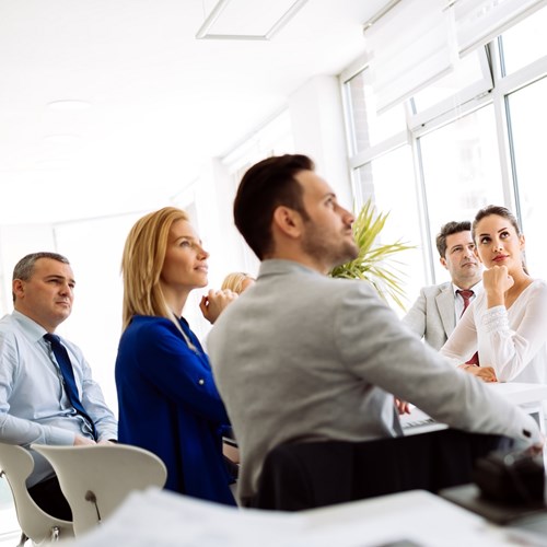 Sapa tools and services Business meeting with several white collar workers around a table, looking towards a presentation
